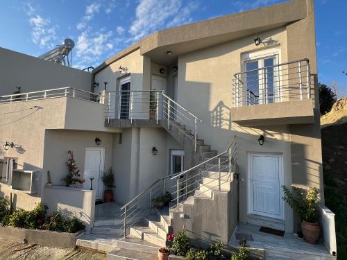 a white house with stairs in front of it at Kourites Apartments in Zarós