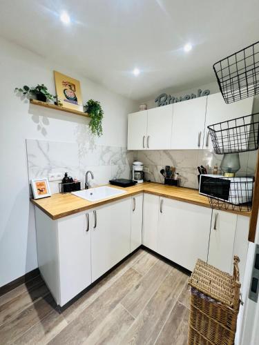 une cuisine avec des armoires blanches et un évier dans l'établissement Petite maison indépendante proche Strasbourg, à Brumath