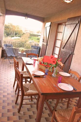 - une table et des chaises en bois sur un balcon avec une table et des fleurs dans l'établissement Maison de campagne mer et montagne, à Sorbo-Ocagnano