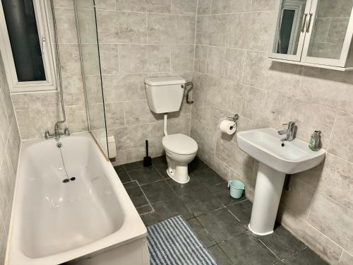 a bathroom with a tub and a toilet and a sink at Central London Private Bedrooms in Finsbury Park Station in London