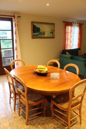 einen Holztisch mit Stühlen und eine Schale Bananen darauf in der Unterkunft Corse Maison de campagne mer et montagne in Sorbo-Ocagnano