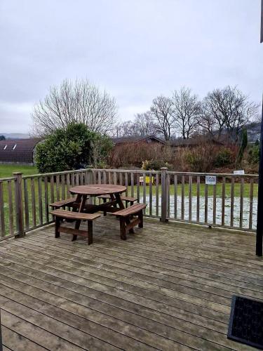a picnic table and benches on a wooden deck at The Ness, Lodge with Hot Tub in Crieff