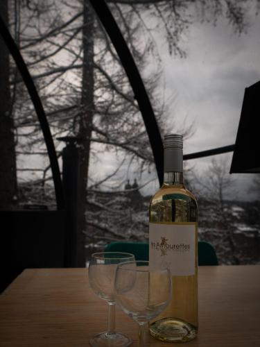 a bottle of wine and two wine glasses on a table at La St Hubsphair in Saint-Hubert