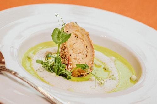 a plate with a piece of food on a green sauce at Hotel Restaurant Zur Neroburg in Neroth