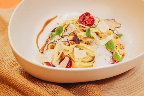 a white bowl filled with pasta on a table at Hotel Restaurant Zur Neroburg in Neroth