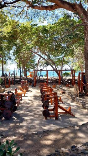 a row of wooden benches sitting next to the water at El Prado: New 2br Condo in Las Catalinas in Playa Danta