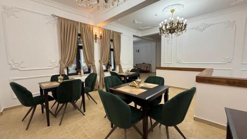 a restaurant with green chairs and tables and a chandelier at La Bulevard in Piteşti