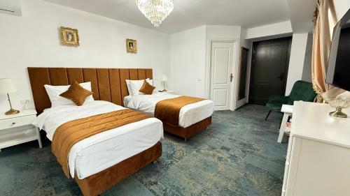 a hotel room with two beds and a chandelier at La Bulevard in Piteşti