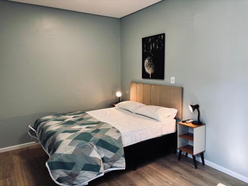 a bedroom with a bed and a table with a lamp at Conforto entre a UFSM e o centro in Santa Maria