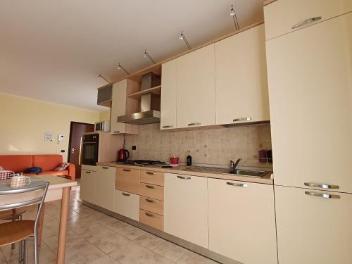 a large kitchen with white cabinets and a table at Appartamento dei Salici in Gallarate