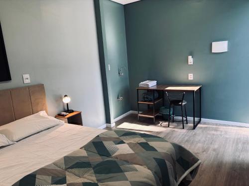 a bedroom with a bed and a desk with a table at Conforto entre a UFSM e o centro in Santa Maria