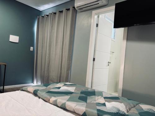 a bedroom with a bed and a window with a bedspread at Conforto entre a UFSM e o centro in Santa Maria