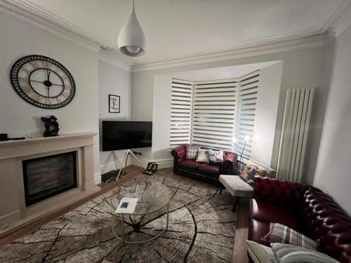 a living room with a fireplace and a clock on the wall at Prospect House in Settle