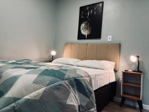 a bedroom with a bed and a picture on the wall at Conforto entre a UFSM e o centro in Santa Maria