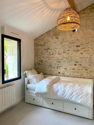 une chambre avec un lit blanc et un mur de briques dans l'établissement Le Lodge du Chêne - Havre de paix près du Futuroscope, à Vendeuvre-du-Poitou