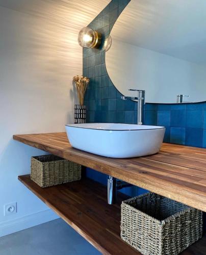 La salle de bains est pourvue d'un lavabo sur un comptoir en bois. dans l'établissement Le Lodge du Chêne - Havre de paix près du Futuroscope, à Vendeuvre-du-Poitou