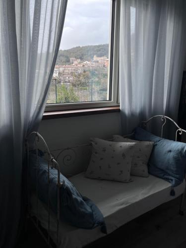a bed with pillows sitting in front of a window at Il giardino di Chiara 1 Rifugio per anime stanche in Serrastretta