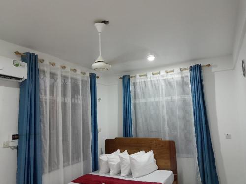 a bedroom with blue curtains and a bed with white pillows at Valley Breeze Hotel in Dar es Salaam