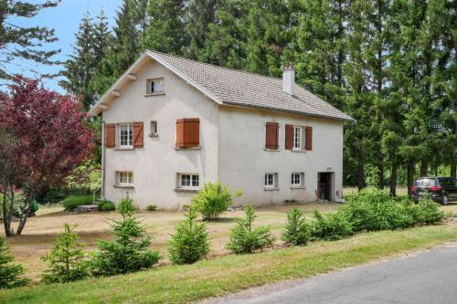 a white house with red shuttered windows in a yard at Maison charmante au cœur du Chambon-sur-Lignon avec jardin in Le Chambon-sur-Lignon