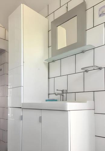 une salle de bain blanche avec un lavabo et un miroir dans l'établissement Maison charmante à Charron avec piscine partagée, à Charron