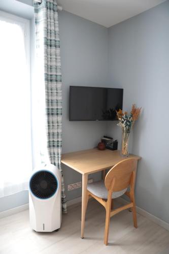 Elle comprend un bureau avec une chaise et une télévision murale. dans l'établissement Appartement élégant - Montmartre, à Paris