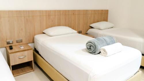 two beds in a small room with white sheets at Hotel Viña Del Mar in Santa Marta