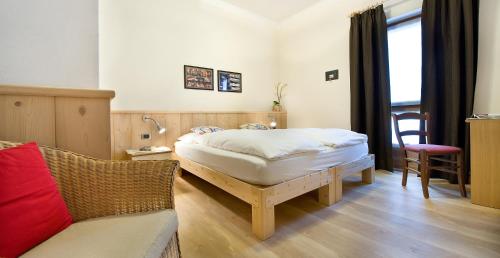 a bedroom with a bed and a chair and a couch at Hotel Alegra in Livigno