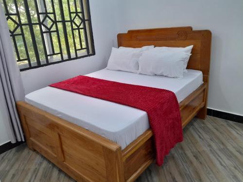 a bedroom with a wooden bed with white sheets and pillows at Valley Breeze Hotel in Dar es Salaam