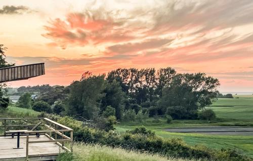 a sunset over a field with a wooden bench at Cozy Home In Sejerø With Wifi in Sejerby