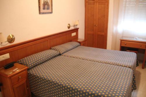 a bedroom with a bed with a wooden head board at Hostal Maribel in Almería