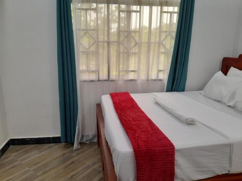 a bedroom with a bed with a red and white blanket at Valley Breeze Hotel in Dar es Salaam