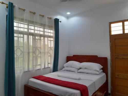 a bedroom with a bed with a window and a red blanket at Valley Breeze Hotel in Dar es Salaam