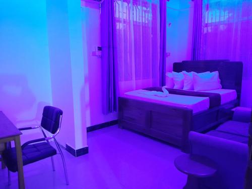 a bedroom with a bed and a chair and purple lights at Valley Breeze Hotel in Dar es Salaam
