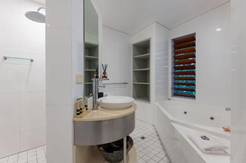 ein weißes Badezimmer mit Waschbecken und Badewanne in der Unterkunft Diamond by the sea - Direct beach access in Newell Beach