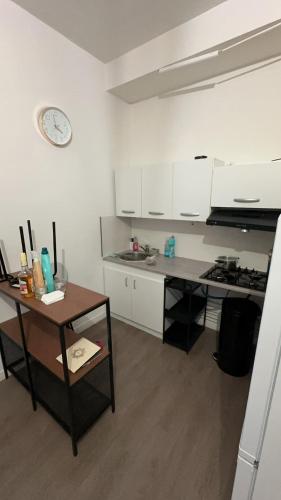 une cuisine avec des placards blancs, une table et une horloge dans l'établissement Apparemment T1 cosy, à Cabriès