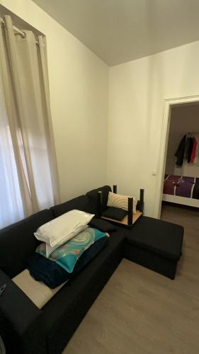 - un canapé noir avec des oreillers dans l'établissement Apparemment T1 cosy, à Cabriès