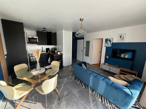 a living room with a blue couch and a table at Le petit écrin de Divonne in Divonne-les-Bains
