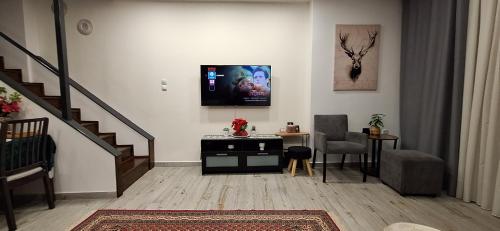 een woonkamer met een trap, een tafel en een televisie bij THOMAS LUXURY APARTMENT in the historical center of Ioannina in Ioannina