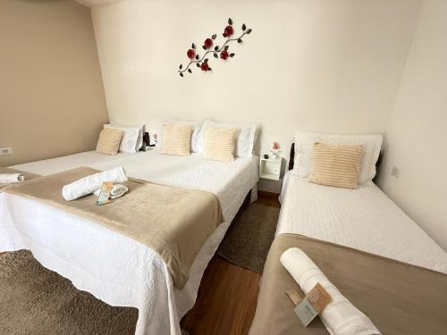 two beds in a room with white walls at Estúdios Recanto Genebra- 15 min Centrinho Turístico in Campos do Jordão