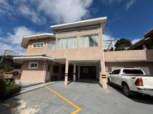 a building with a car parked in a parking lot at Estúdios Recanto Genebra- 15 min Centrinho Turístico in Campos do Jordão