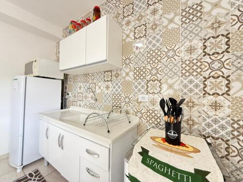 a kitchen with a sink and a white refrigerator at Estúdios Recanto Genebra- 15 min Centrinho Turístico in Campos do Jordão