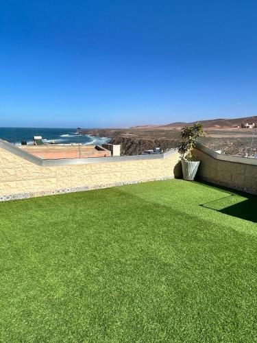 a yard with green grass and a view of the ocean at Tirazir House 3 in Mirleft