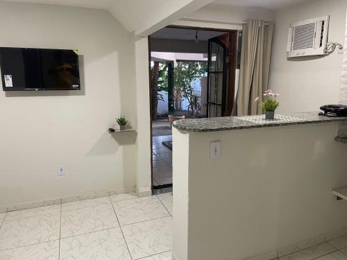a kitchen with a counter and a tv on the wall at Suíte 4 Caminho do Mirante in Iguaba Grande