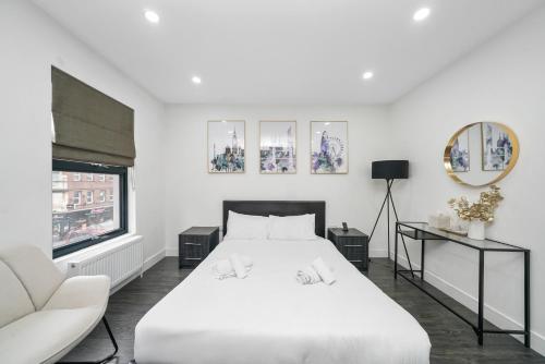 a white bedroom with a white bed and a window at Skyline Studios Tower Bridge in London