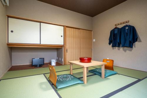a room with a table and chairs and a coat at Ryokan Yamazaki in Kyoto