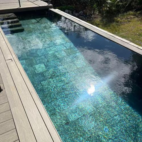 a swimming pool with blue water and a wooden deck at Mau Lakaz in Belle Mare
