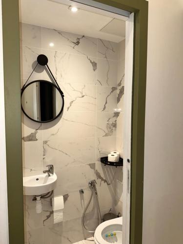 une salle de bain blanche avec un lavabo et un miroir dans l'établissement Joli appartement avec cheminée, à Paris