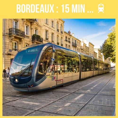 un tramway dans une rue en face d'un bâtiment dans l'établissement Appart cosy et terrasse en ville, à Mérignac
