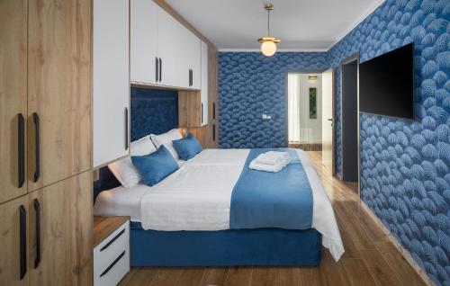 a bedroom with a large bed with a blue accent wall at Lovely Home In Funtana With Sauna in Funtana