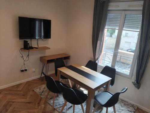 a dining room with a table and chairs and a television at Très bel appartement à Paris et La Défense in La Garenne-Colombes